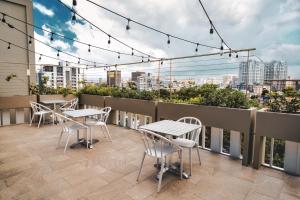 een balkon met tafels en stoelen en een skyline van de stad bij The Wave Hotel Condado in San Juan