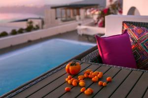 une pile d'oranges assises sur une table à côté d'une piscine dans l'établissement Abelonas Retreat, à Imerovigli