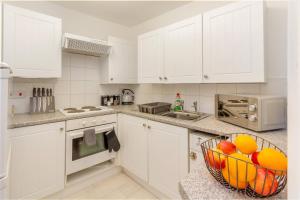 a kitchen with white cabinets and a basket of fruit at Guest Homes - New Street Suite in Worcester