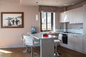 a kitchen with white cabinets and a island with white chairs at Fenetre sur le blue in Taormina