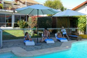 a group of people sitting on lounge chairs next to a pool at Bernie's Bed & Breakfast , A 3 KILOMETROS DEL AEROP EZEIZA, VAN ,IN-OUT, FREE EZEIZA AIRPORT in Ezeiza