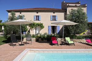 una casa con sillas y sombrillas junto a una piscina en Au Mas du Soleil, en Senouillac