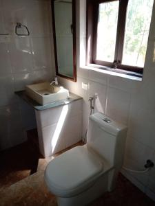 a bathroom with a white toilet and a sink at Kwality Estate in Madikeri