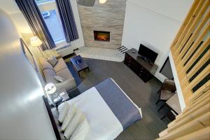 Hotel Vacances Tremblant في مونت تريمبلانت: غرفة نوم مع سرير وغرفة معيشة مع موقد