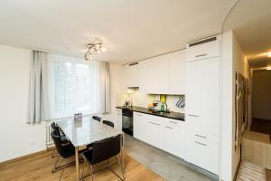 una cocina con armarios blancos y una mesa con sillas. en Apartment Kesch Chesa Quadrella, en Pontresina
