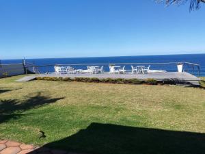 d'une terrasse avec des tables et des chaises blanches et l'océan. dans l'établissement Ocean Hideaway Bed and Breakfast, à Amanzimtoti