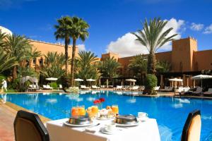 a table with drinks on it next to a swimming pool at Berbère Palace in Ouarzazate