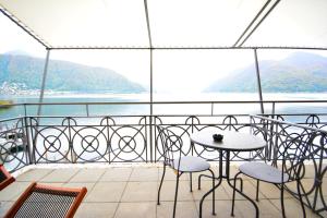 uma varanda com mesa e cadeiras e vista para a água em Lac Hotel em Melide