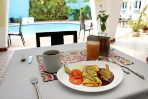 a table with a plate of food and a cup of juice at Hotel Berny in Isla Mujeres