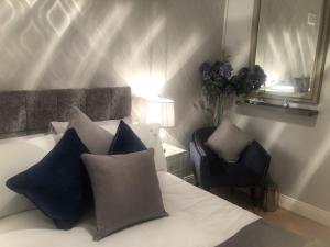 ein Schlafzimmer mit einem Bett mit blauen Kissen und einem Stuhl in der Unterkunft Beechtree House in Dublin