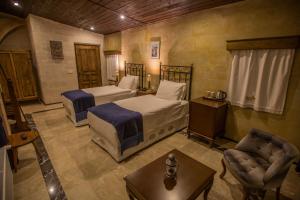 a bedroom with two beds and a couch and a table at Lavender Cave Hotel in Nevşehir
