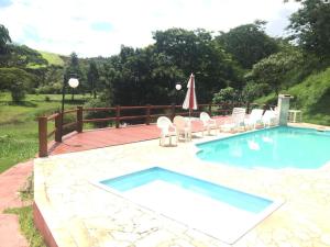 a swimming pool with chairs and an umbrella at Hotel Nosso Sonho in Itatiba