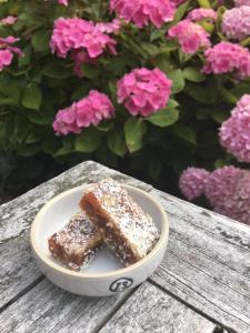 a piece of cake in a bowl on a table with flowers at Ontbijt bij De Boerenmeid in Hoogwoud
