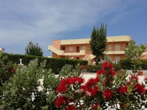 ein Gebäude mit roten Blumen davor in der Unterkunft Stella di Mare Appartamenti in Marsala