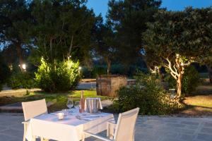 a white table and chairs in a garden at night at Masseria Mongiò dell'Elefante in Otranto