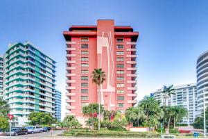 un edificio alto de color rojo con palmeras y edificios en Inviting condo with pool & beach access, en Miami Beach