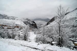 una montagna innevata con alberi e case in una città di Hotel Restaurante Valdevenados ad Anguiano