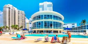a building with people sitting in chairs in front of a pool at Oceanview studio - on beach, gym, bars, and free parking! in Miami Beach