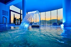 a water fountain in a swimming pool with the sunset at Seehotel Pilatus in Hergiswil