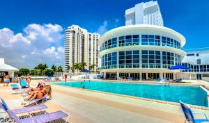una piscina en un complejo con gente sentada en sillas en Gorgeous Oceanfront Penthouse with gym, bars, beach access and free parking!, en Miami Beach