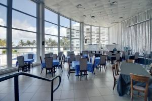 a restaurant with blue tables and chairs and windows at Oceanfront Townhouse with direct access to the Beach! Steps from the sand! in Miami Beach