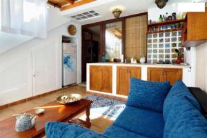een woonkamer met een blauwe bank en een keuken bij Estudio Sherazad in Tías