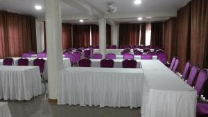 una sala conferenze con tavoli bianchi e sedie viola di MakanHill Resort Hotel a Mityana