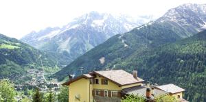 a house on a hill with mountains in the background at Albergo Eden in Ponte di Legno