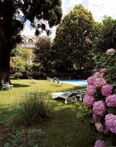 un parco con piscina e alcuni fiori rosa di Hotel Greif a Bolzano