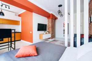 Schlafzimmer mit orangefarbenen Wänden, einem Bett und einem TV in der Unterkunft Apartments Nezavisomosti 44 in Minsk