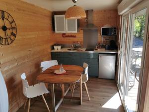 uma cozinha com uma mesa de madeira e cadeiras brancas em Chalet-studio Bien-Hetre em Fichous-Riumayou