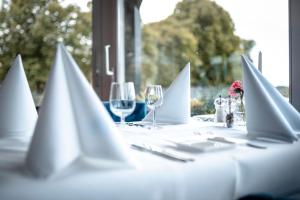 una mesa blanca con copas de vino y servilletas. en Hotel Restaurant De Stadsherberg en Franeker