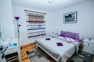 a bedroom with a bed with purple sheets and a window at Lux Apartment in Žabljak