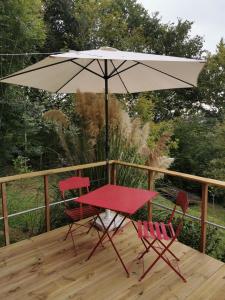 a table and two chairs under an umbrella on a deck at La roulotte de Fichous in Fichous-Riumayou
