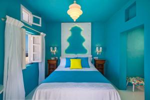 ein blaues Schlafzimmer mit einem Bett und einem gelben Kissen in der Unterkunft Barocco Bello Studio in Fira