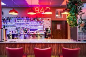 a bar with red chairs and a bar counter with a barvisor at Hôtel Siatel Besançon Chateaufarine in Besançon