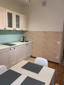 モスクワにあるApart-Hotel Just-Mの白いキャビネット、テーブルと椅子付きのキッチンが備わります。