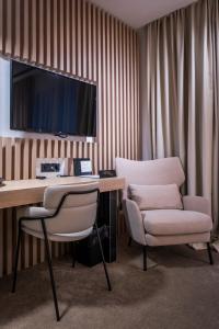 a room with a desk and a chair and a television at Pod Zidom Rooms in Zagreb