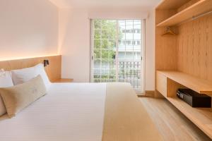 Un dormitorio con una gran cama blanca y una ventana en Reforma Guest House en Ciudad de México