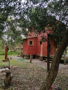 a red cabin in the middle of a forest at Ligustrum House in Punta Del Diablo +3 photos