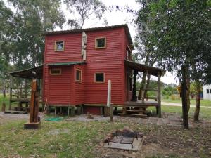 una casa roja con techo de gambrel en Ligustrum House, en Punta del Diablo