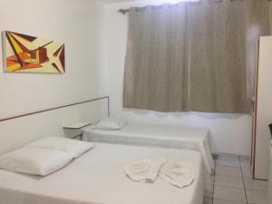 2 camas en una habitación con ventana en Hotel Miranelli, en Barbacena