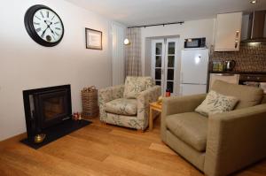 a living room with a couch and a clock on the wall at Newton Cottage South in Inveraray