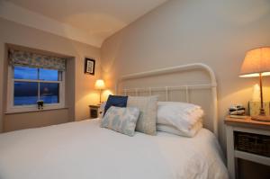 a bedroom with a white bed with pillows and a window at Newton Cottage South in Inveraray