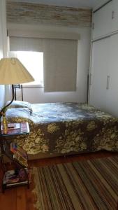1 dormitorio con 1 cama con lámpara y ventana en Praia de Itapuã, en Río de Janeiro