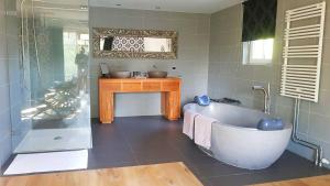 a bathroom with a bath tub and a sink at Bed and breakfast Mooi Achel in Achel