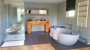 ein Badezimmer mit einer Badewanne und einem Waschbecken in der Unterkunft Bed and breakfast Mooi Achel in Achel