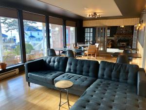 un salon avec un canapé bleu, des tables et des fenêtres dans l'établissement Bleu Mer, hôtel & résidences, à Carleton-sur-Mer