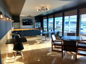 una sala da pranzo con tavoli, sedie e finestre di Bleu Mer, hôtel & résidences a Carleton-sur-Mer