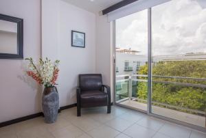 una habitación con una silla y un jarrón con flores en San Pedro Hotel, 5ta Avenida en Playa del Carmen
